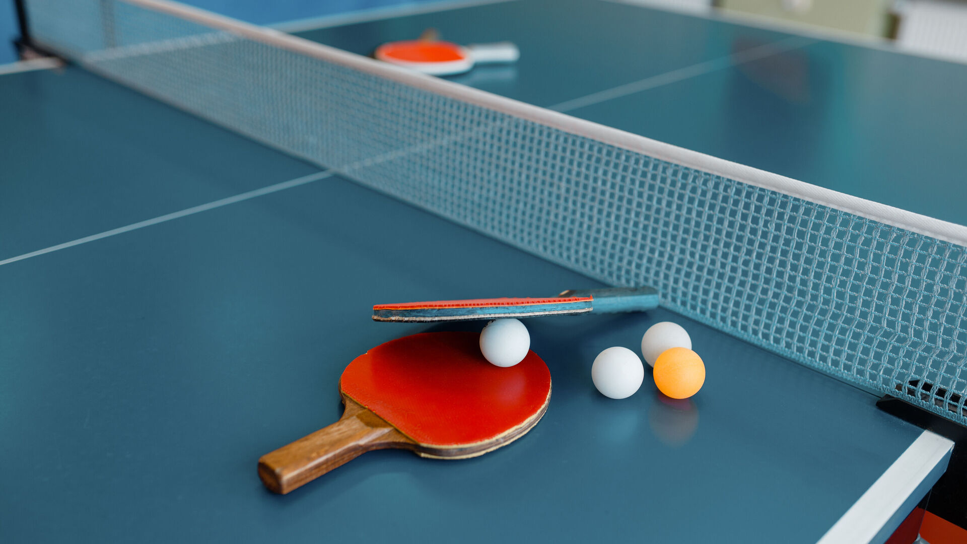 Tischtennisschläger und -bälle liegen auf einem Tischtennistisch