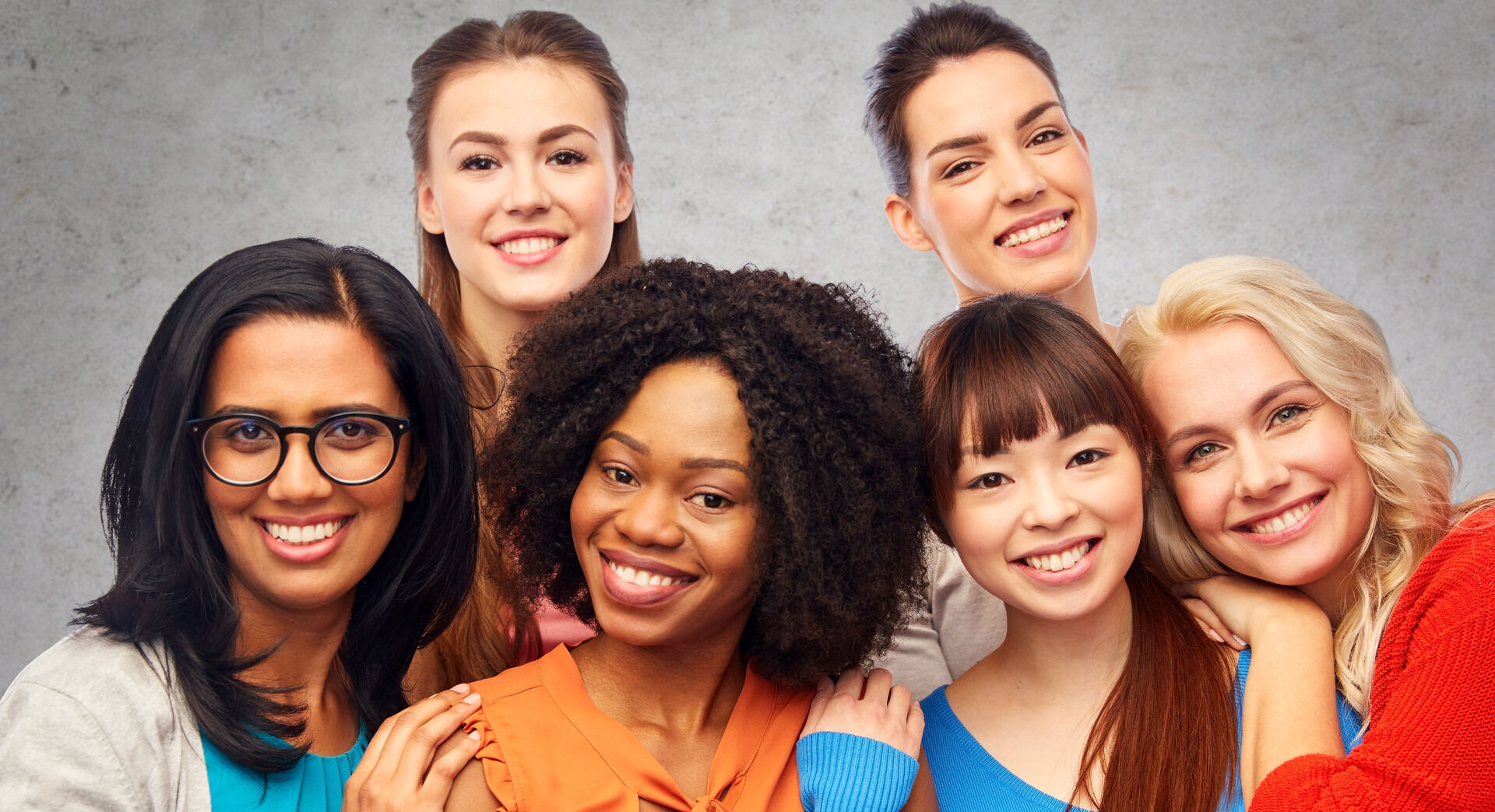 Sechs Frauen verschiedener ethnischer Herkunft lachen in die Kamera.