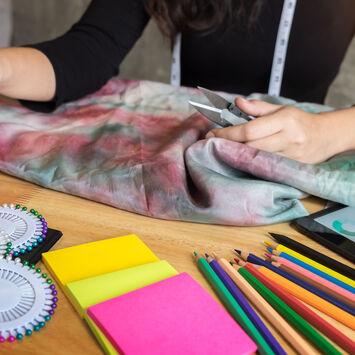Die Hände einer Frau mit allerlei buntem Näh- und Bastelzubehör am Tisch