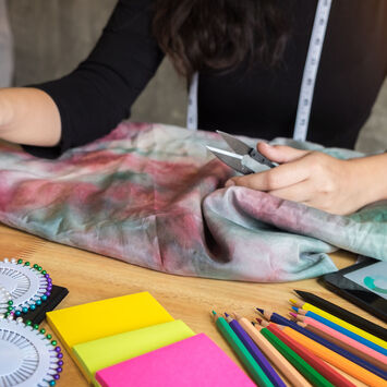 Die Hände einer Frau mit allerlei buntem Näh- und Bastelzubehör am Tisch