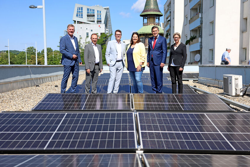 Michael Strebl (Wien Energie), Gerald Bischof (Bezirksvorsteher), Jürgen Czernohorszky (Klimastadtrat), Kathrin Gaál (Vizebürgermeisterin & Wohnbaustadträtin), Peter Hanke (Wirtschaftsstadtrat) und Karin Ramser (Wiener Wohnen) besichtigen die neue PV-Anlage am Gemeindebau in Liesing.