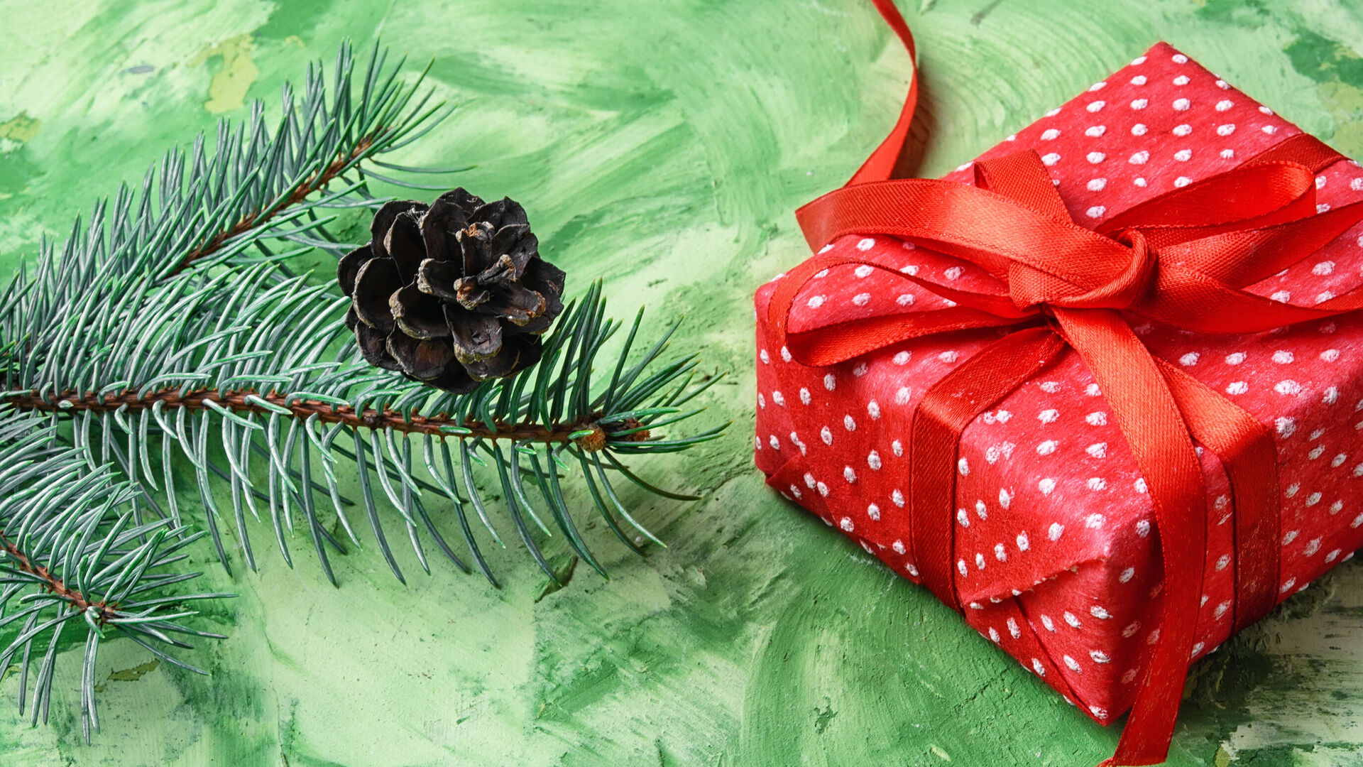 Weihnachtsdekoration: Ein Tannenzweig, ein Tannenzapfen, ein Weihnachtsgeschenk mit rotem Geschenkpapier und roter Schleife