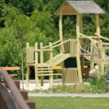 Eine Frau steht auf einer Holzbrücke in den Blumengärten Hirschstetten, im Hintergrund sieht man einen Spielplatz.