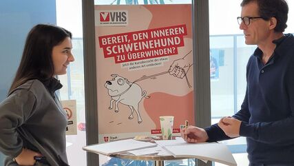 Zwei Personen im Gespräch, stehend an einem Stehtisch