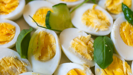 halbierte hartgekochte Eier, mit Basilikumblättern präsentiert