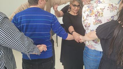 Mehrere Personen halten sich an den Händen und versuchen offenbar diese Menschenkette zu entwirren. Schulungs-/Workshopsituation