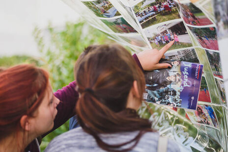 Besucherinnen schauen sich Fotos des Hoffestes an.