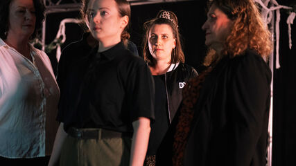 Mehrere Personen stehen mit starrem Blick sehr nahe beieinander, jeder blickt in eine andere Richtung.