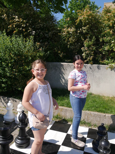 Kinder genießen das tolle Wetter und spielen eine Partie Schach.