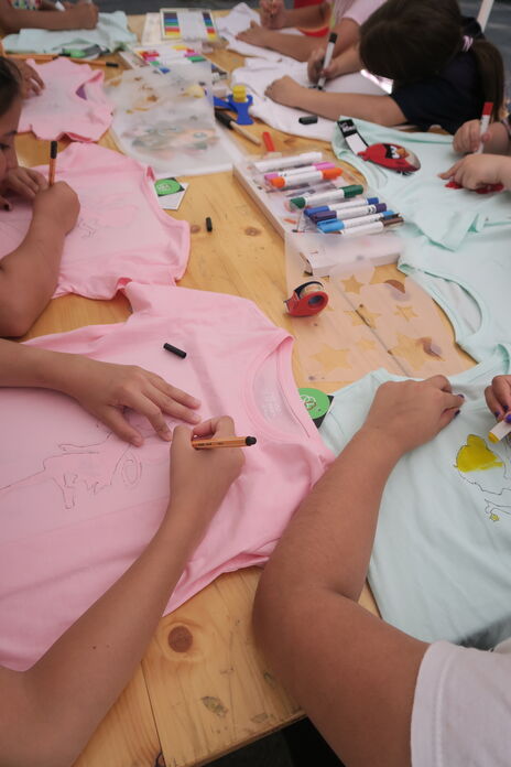 Kinder bei Zeit für Kreativität bemalen T-Shirts und Leinwände