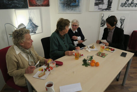 Besucherinnen essen beim Jahresausklang gemeinsam mit wohnpartner-Mitarbeiterin