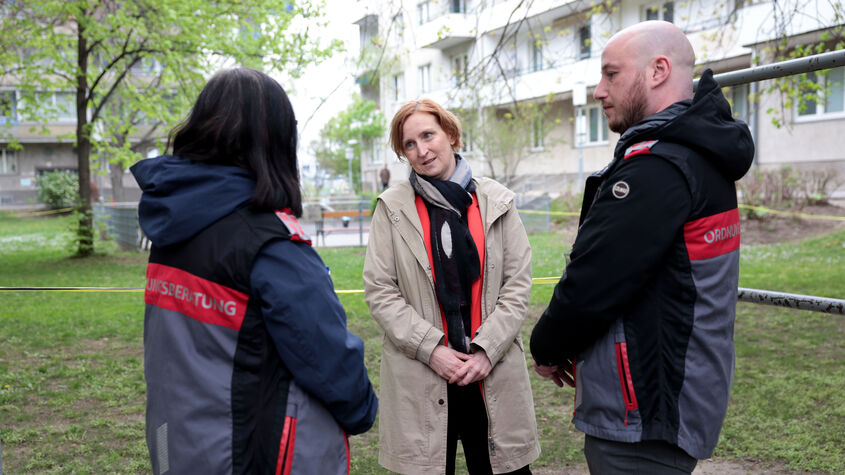Zwei Ordnungsberater*innen von hinten im Gespräch mit Elke Hanel-Torsch, der Wohnbaustadträtin.