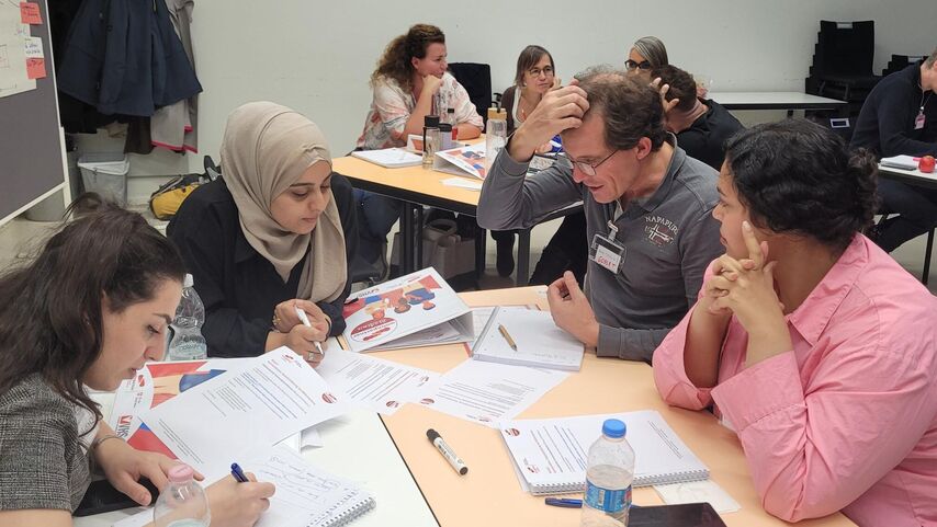 Vier Personen sitzen um einen Tisch und sind in eine Gruppenarbeit vertieft.