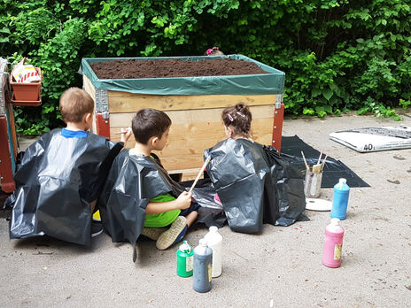 Kinder bemalen das Hochbeet