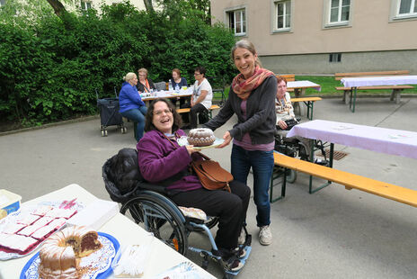 Eine Bewohnerin bringt einen Kuchen für das tolle Nachspeisenbuffet.