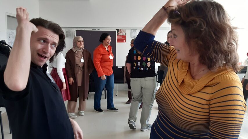 Zwei Personen im Vordergrund die kurz davor sind, mit den Händen einzuschlagen. 