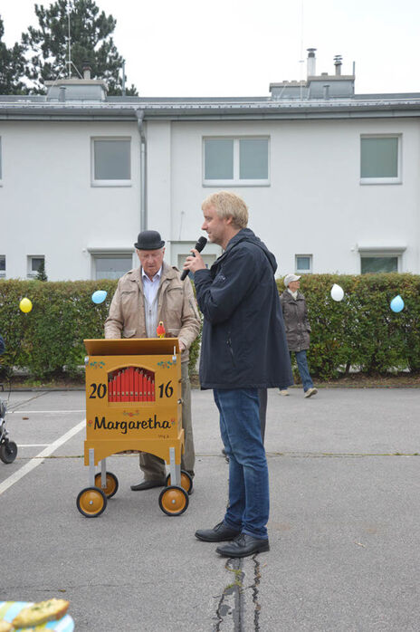 Offizielle Worte und ein Drehorgelspieler.