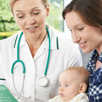 Eine Ärztin berät eine junge Mutter mit Baby im Arm.