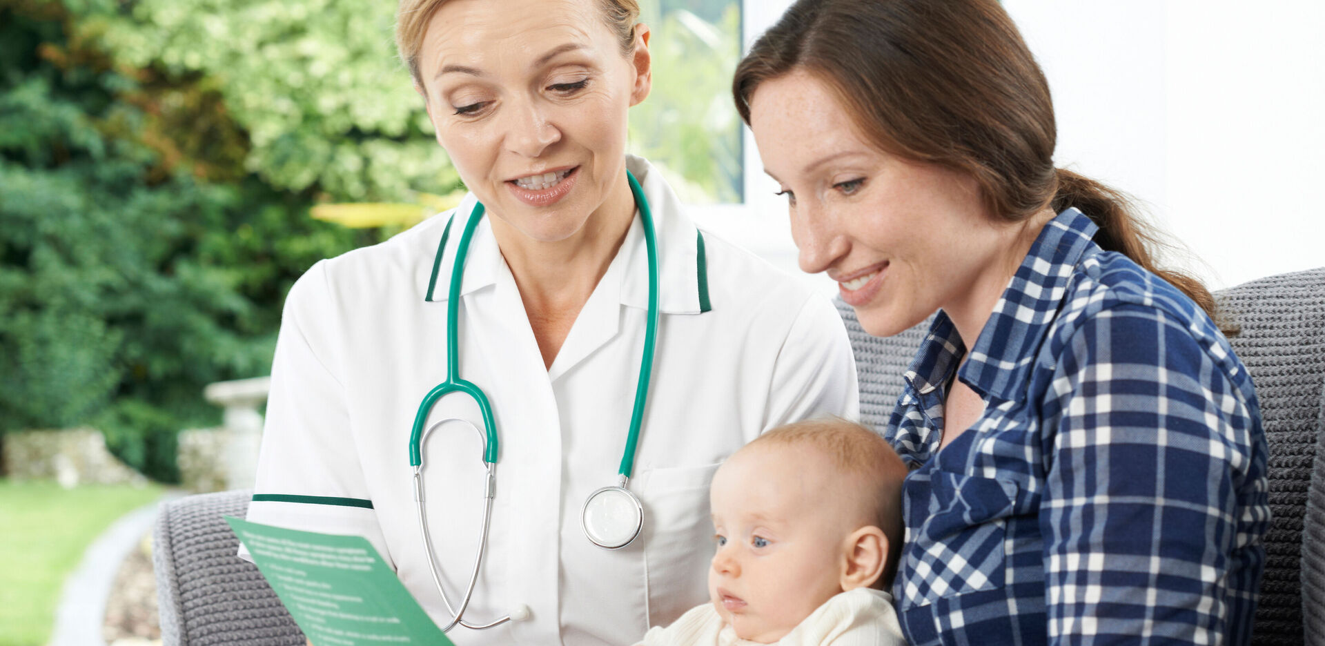 Eine Ärztin berät eine junge Mutter mit Baby im Arm.
