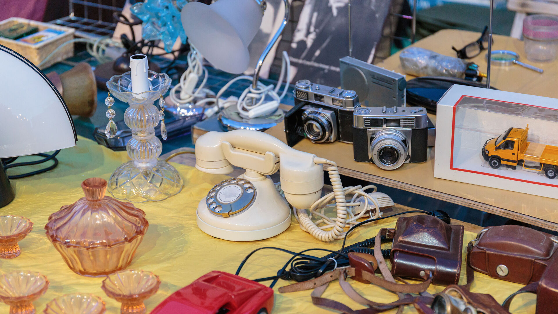 Flohmarkt-Ware auf einem Tisch: alte Telefone, Fotoapparate, Lampen, etc.