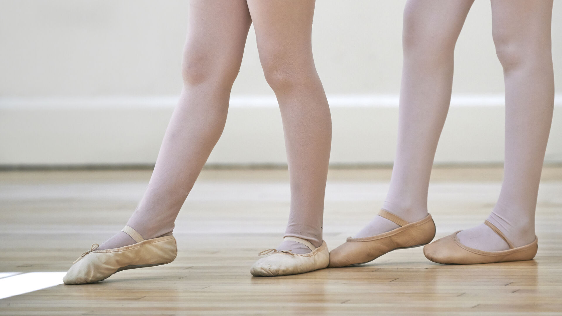 2 Paar Kinderbeine mit weißen Strumpfhosen und Ballettschuhen