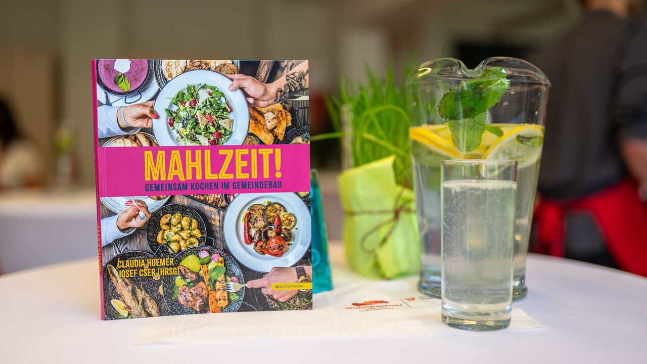 Kochbuch "Mahlzeit" auf einem Tisch nebst Wasserkaraffe mit Wasser und Minzblättern
