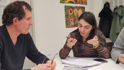  Zwei Personen im Gespräch, an einem Tisch sitzend. Schulungssituation