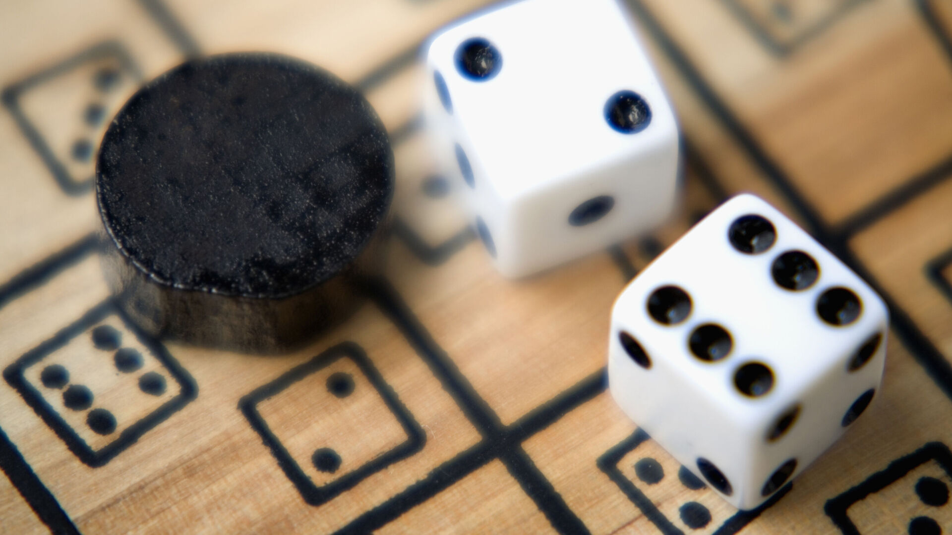 Zwei Würfel und ein Spielstein auf einem Spielebrett aus Holz