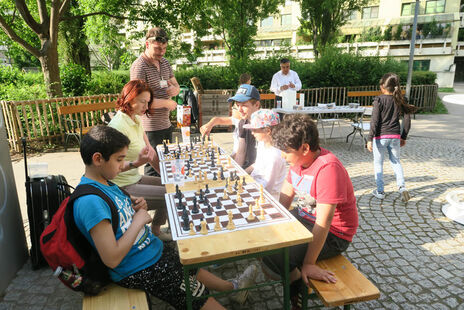 Kinder und Erwachsene spielen Schach.