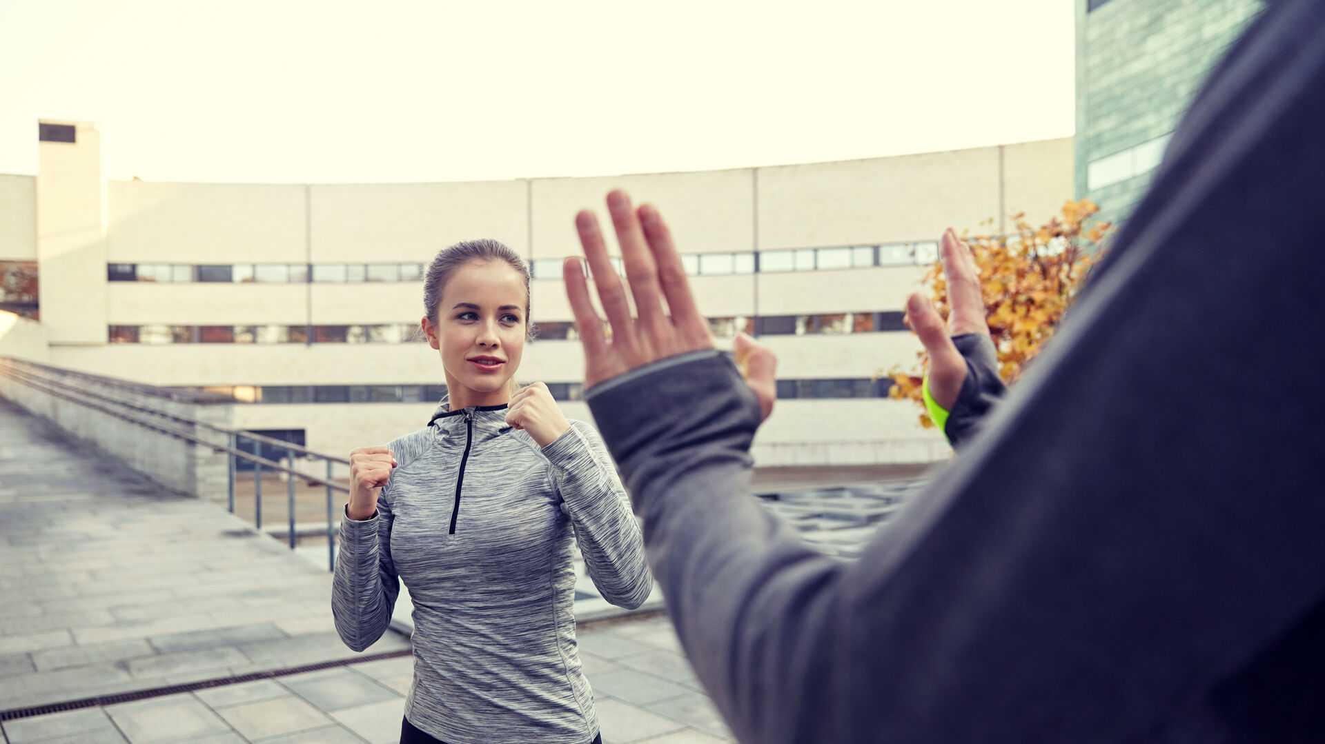 Frau in Sportkleidung übt Selbstverteidigung mit einem Partner im Freien