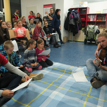 Kinder singen mit Gitarre-Spieler