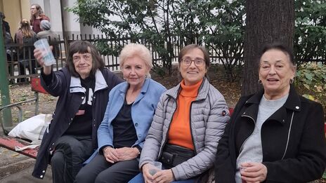 4 Besucherinnen des Nachbarschaftsfestes sitzen auf einer Parkbank im Innenhof und lachen