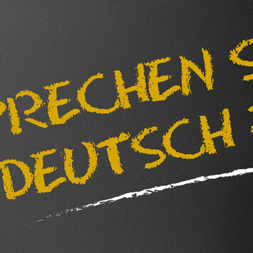 Der Schriftzug "Sprechen Sie Deutsch?" mit Kreide auf eine schwarze Tafel geschrieben