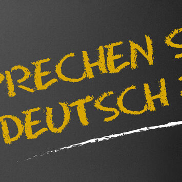 Der Schriftzug "Sprechen Sie Deutsch?" mit Kreide auf eine schwarze Tafel geschrieben
