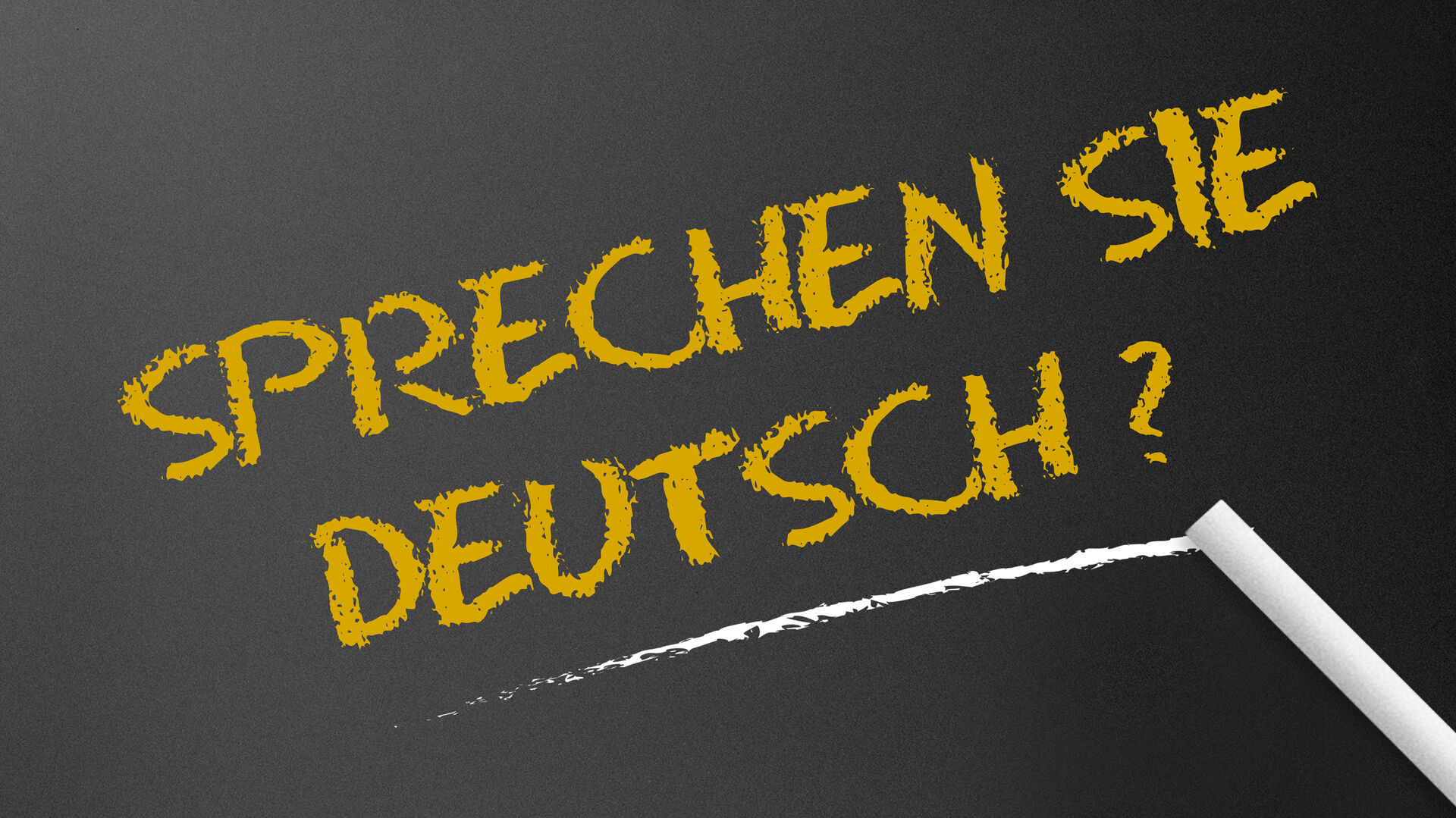 Der Schriftzug "Sprechen Sie Deutsch?" mit Kreide auf eine schwarze Tafel geschrieben