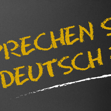 Der Schriftzug "Sprechen Sie Deutsch?" mit Kreide auf eine schwarze Tafel geschrieben