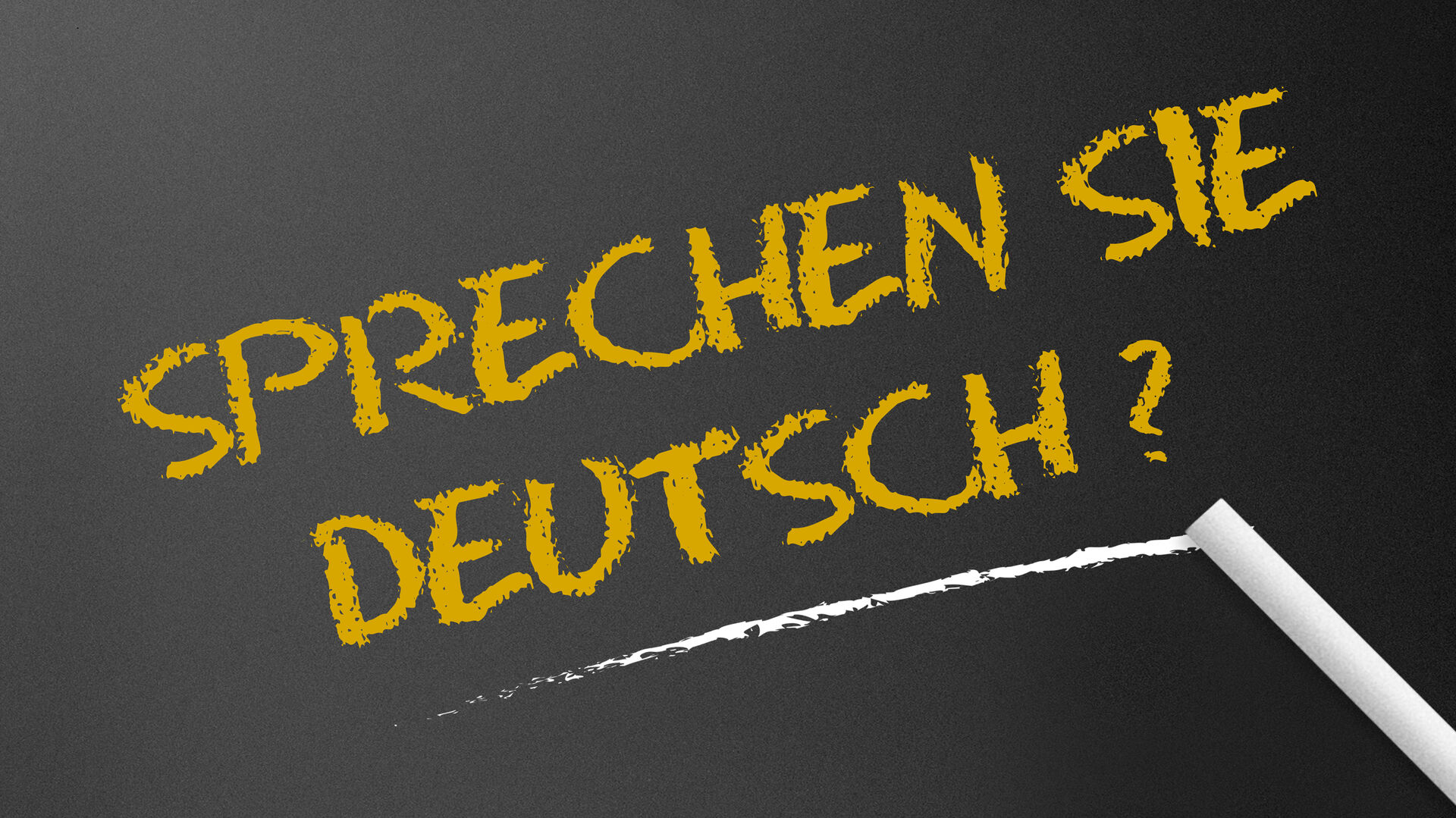 Der Schriftzug "Sprechen Sie Deutsch?" mit Kreide auf eine schwarze Tafel geschrieben