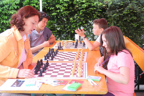 Eltern spielen gegen ihre Kinder Schach.