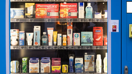 Verkaufsautomat mit verschiedenen Medikamenten und Pflegeprodukten in Verpackungen hinter einer Glasscheibe