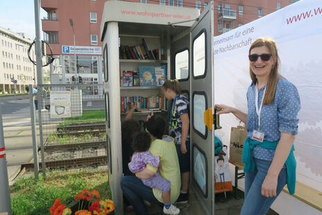 wohnpartner-Mitarbeiterin öffnet Tür zur BücherKABINE für Leseratten