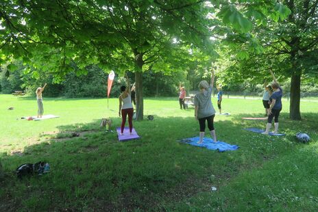 Bewohnerinnen auf Wiese mit Yogalehrerin