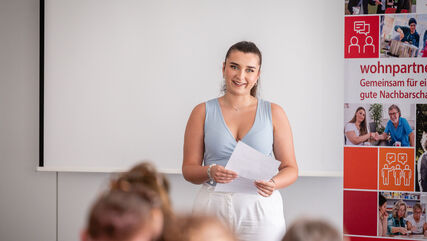 Eine junge Frau hält eine Rede vor der Abschlussklasse des 2. Jahrgangs der wohnpartner-Akademie