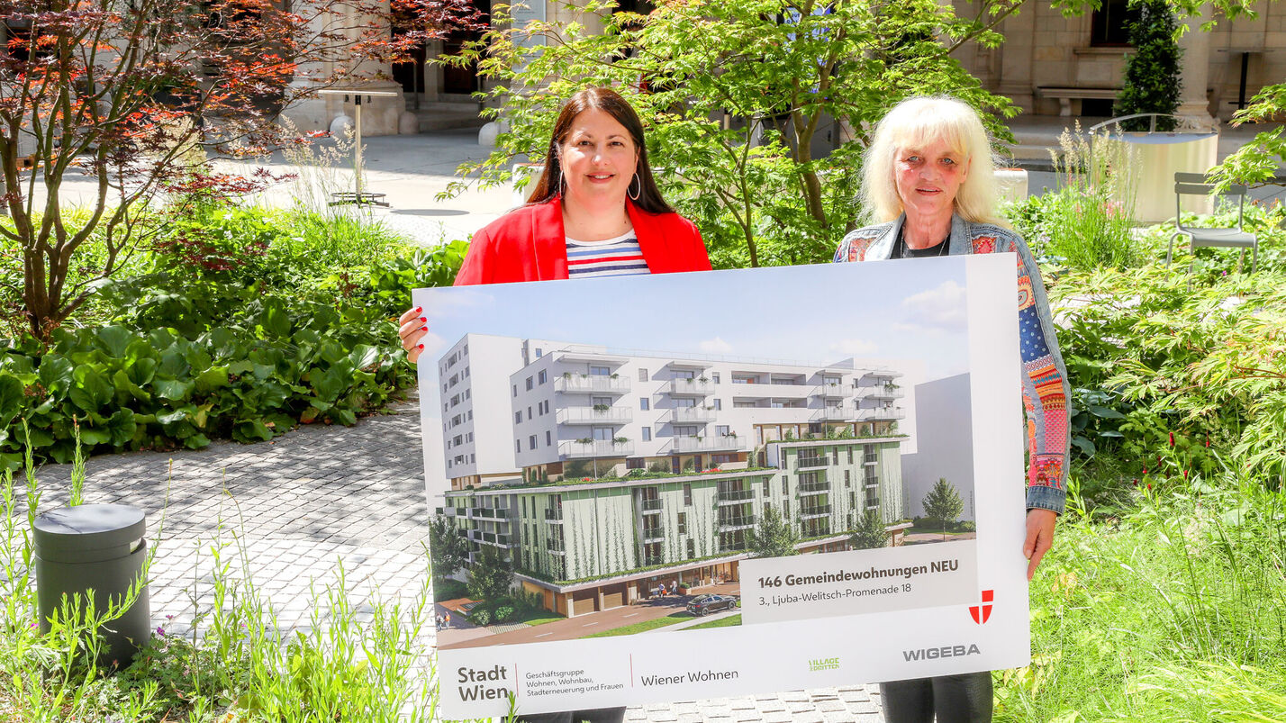 Vizebürgermeisterin Kathrin Gaal hält gemeinsam mit der Bezirksvorsteher-Stellvertreterin des dritten Bezirks, Susanne Wessely eine Tafel, die eine Visualisierung des Gemeindebau NEU im Village im Dritten zeigt.