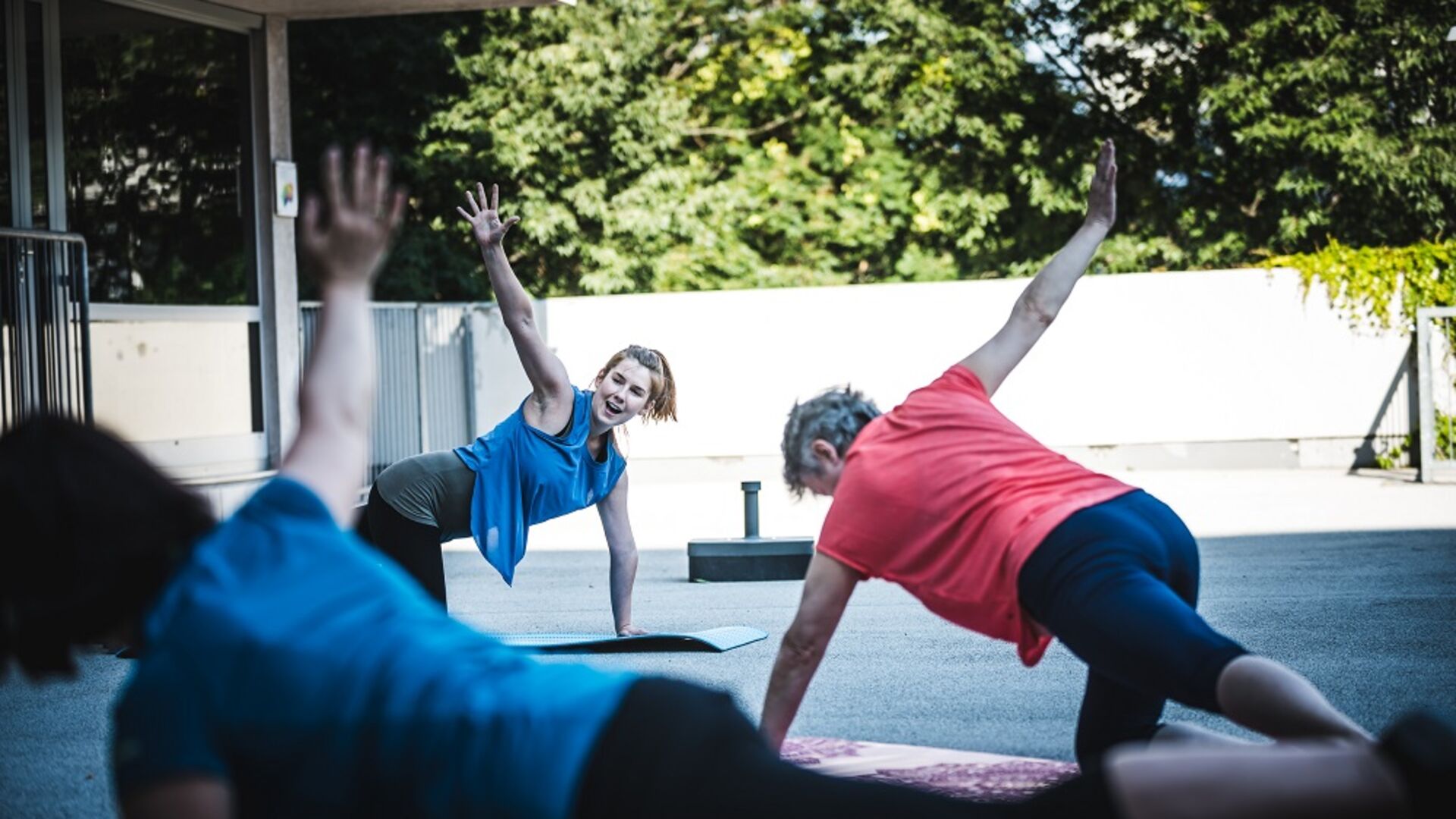 Eine Gruppe Frauen führen auf Gymnastikmatten am Boden Pilates-Übungen aus.