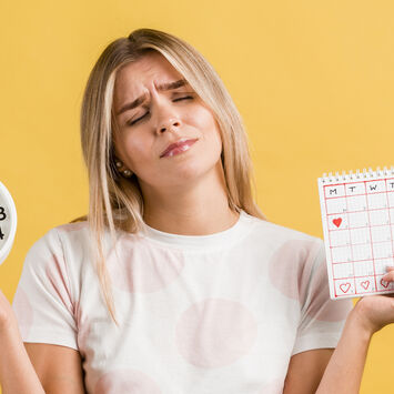 Eine Frau hält eine Uhr in einer Hand und einen Menstruationskalender in der anderen Hand.