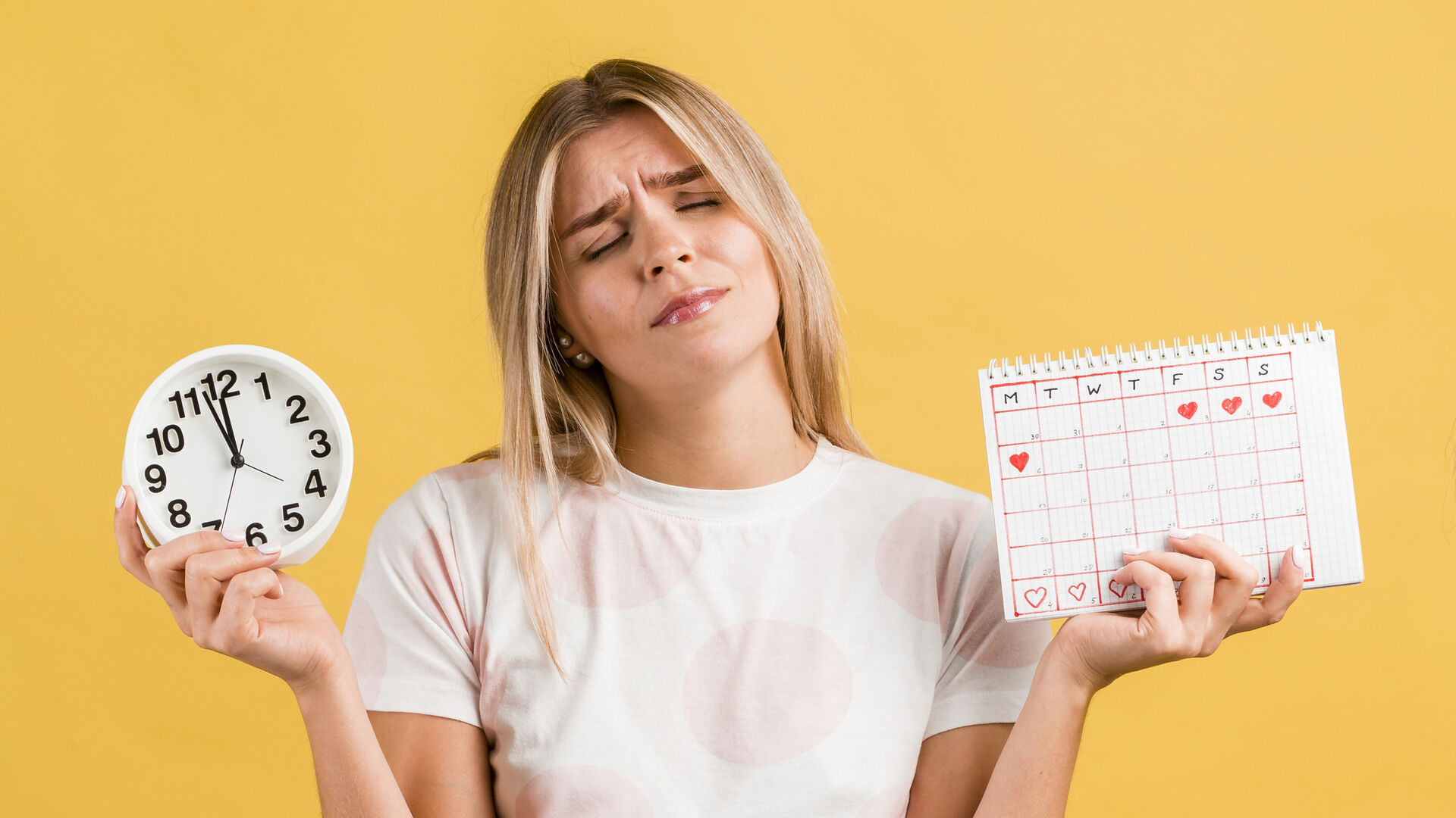 Eine Frau hält eine Uhr in einer Hand und einen Menstruationskalender in der anderen Hand.