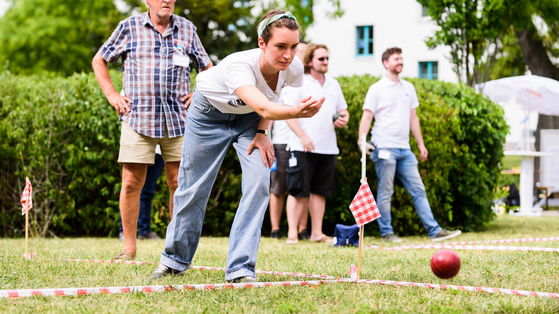 Mehrere Menschen, die auf einem Rasen Boccia spielen.