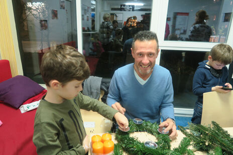 Vater mit Sohn beim Adventkranzbinden