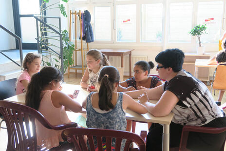 Kinder spielen Karten unter Anleitung.