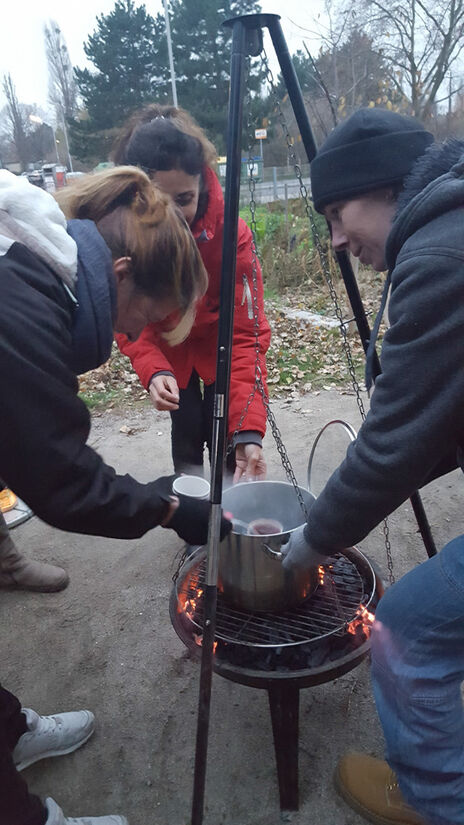 BewohnerInnen entnehmen Punsch aus Kochtopf am Griller